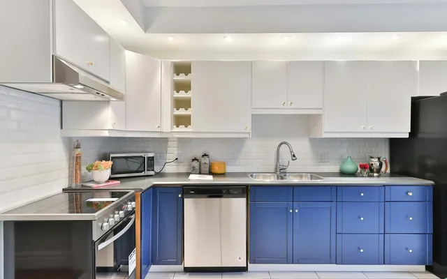 Kitchen with white upper cabinets and blue painted lower cabinets
